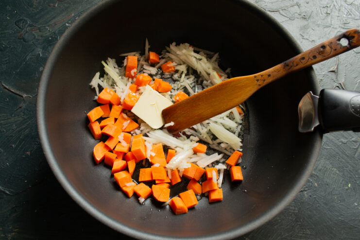 Sautéing the vegetables Diced carrots and onions sautéing with butter in a skillet