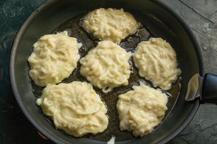 Frying the tsybulnyky Onion fritters cooking in a hot oiled skillet.