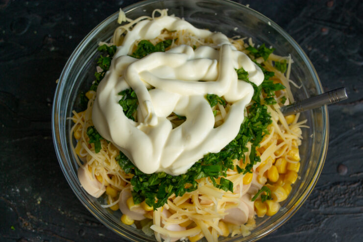 Dressing with mayonnaise Mayonnaise added to the salad ingredients in a glass bowl.