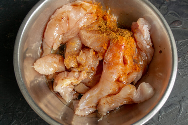 Marinating the chicken Mixing raw chicken strips with soy sauce and paprika in a bowl