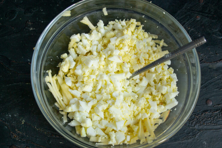 Adding chopped eggs Finely diced hard-boiled eggs in a salad bowl.