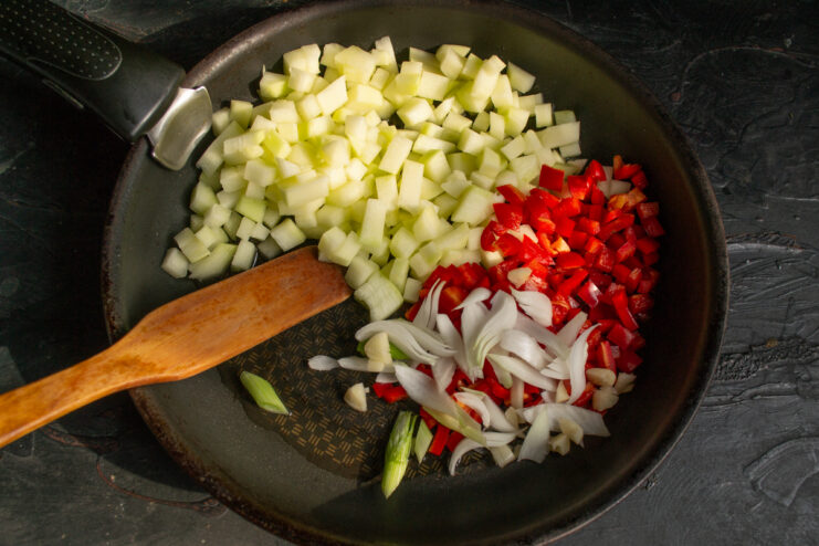 Finely chopped white onion added to the vegetables in the pan.