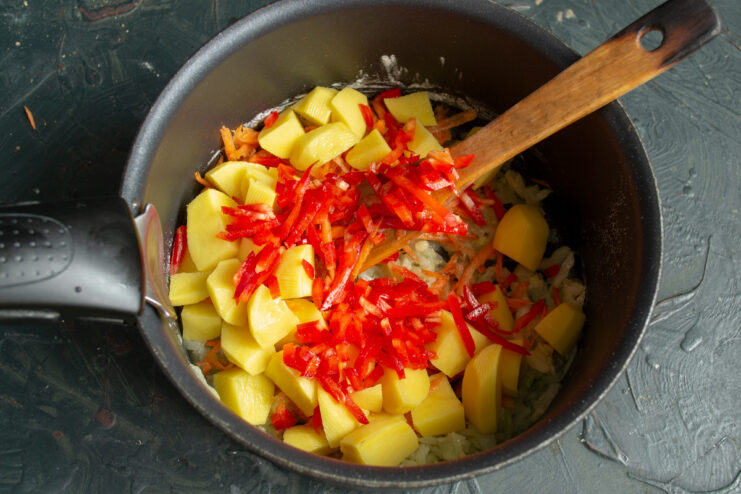 Adding bell pepper Mixing finely chopped sweet red bell pepper into the vegetable base