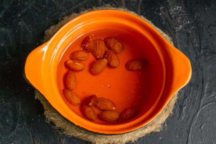 Soaking the almonds Almonds soaking in hot water in an orange saucepan.