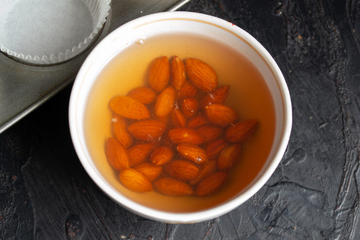 Whole almonds soaking in a bowl of hot water