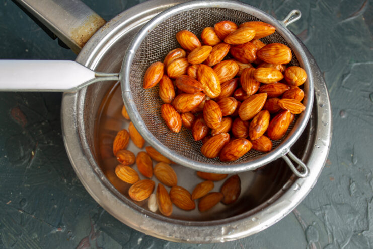 Blanched almonds resting in a fine mesh sieve after being rinsed with cold water