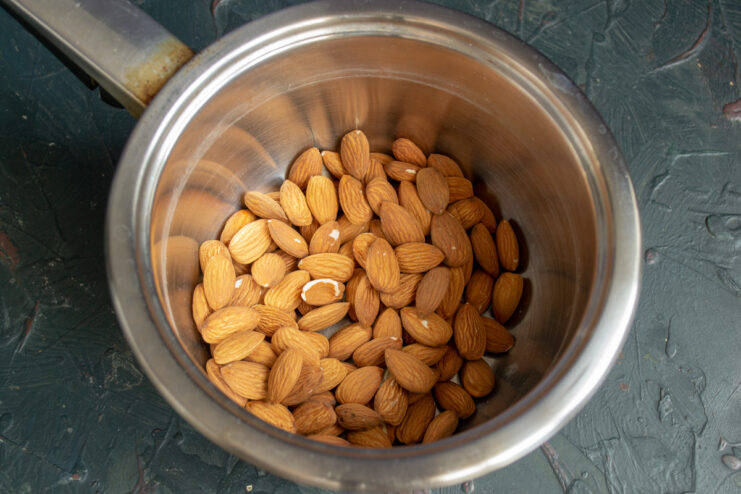 Whole almonds submerged in boiling water in a metal saucepan