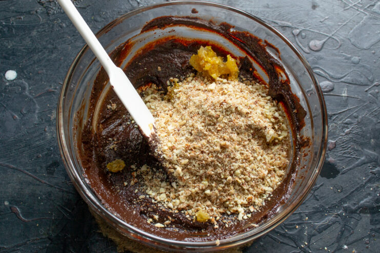 Adding coarsely chopped almonds Folding coarsely crushed toasted almonds into the thick chocolate base