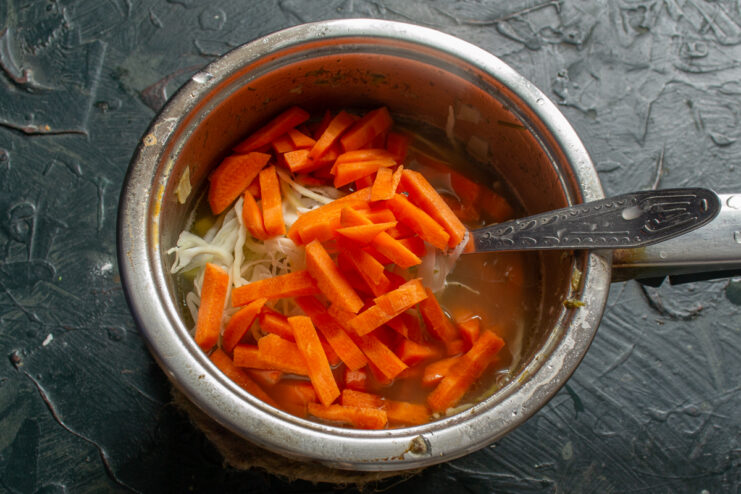 Adding the Carrots Matchstick-cut carrots being added to a pot of simmering vegetables.