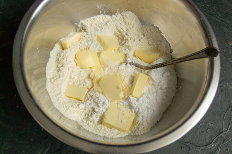 Making the buttery crumbs Rubbing cold butter into flour in a bowl to make pastry crumbs
