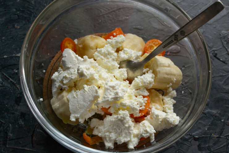 Adding farmers cheese Soft farmers cheese added to a bowl with mashed banana and kumquats