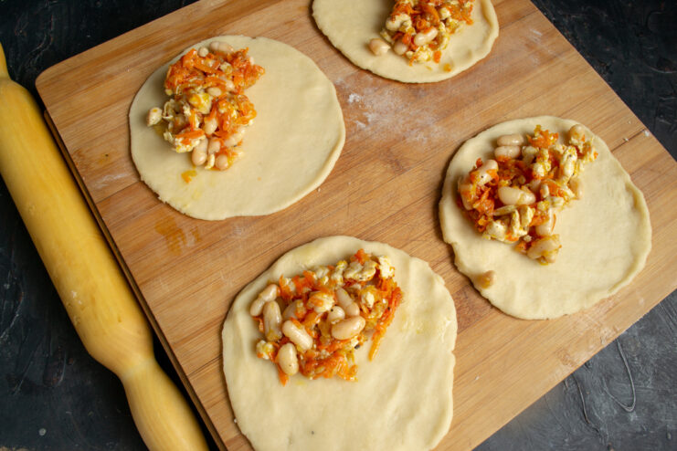 Placing filling on the dough Chicken and bean filling placed on the edges of the dough circles