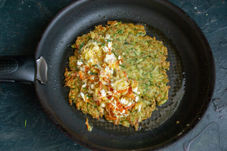 Stuffing the pocket Adding cheese and vegetable filling to half of a zucchini pancake.