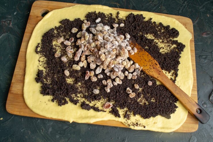 Adding the Filling Spreading poppy seed filling and raisins on rolled dough