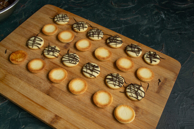 Decorating With Chocolate Drizzling melted dark chocolate in a zigzag pattern over cookie halves