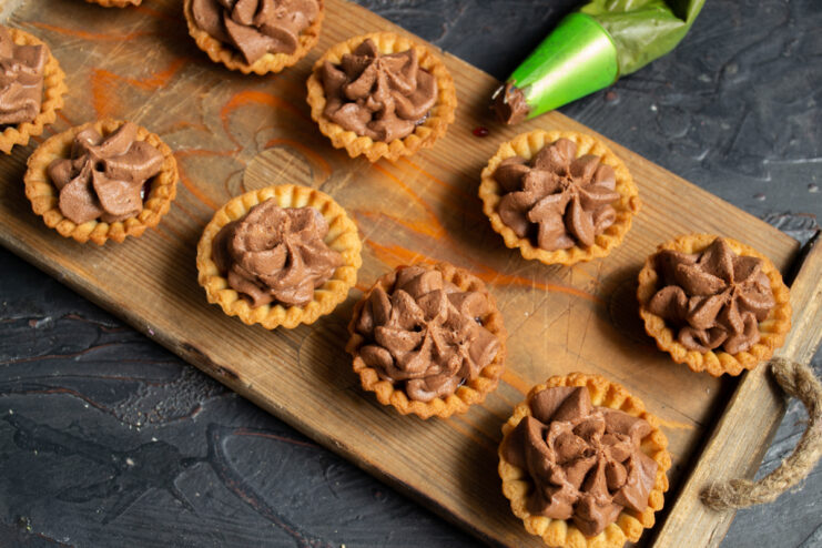 Filling the petits fours Piping chocolate mousse into the pastry shells using a pastry bag