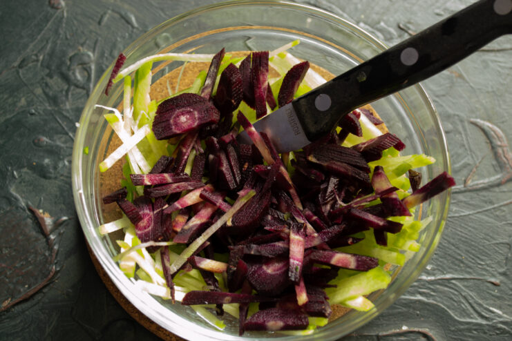 Adding Purple Carrots Sliced purple carrots added to green radish in a salad bowl
