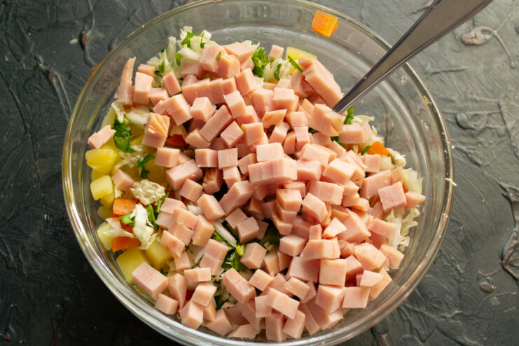 Adding the ham Diced ham in a bowl with salad ingredients