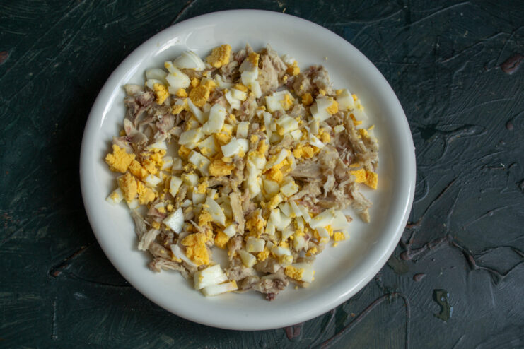 First salad layer: chicken and eggs Diced chicken and boiled eggs spread on a platter