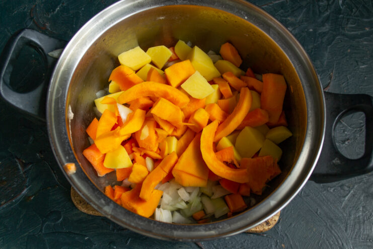 Sliced pumpkin flesh added to the vegetables inside the cooking pot
