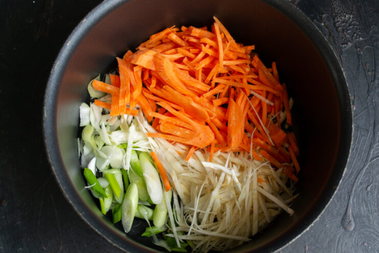 Prepping The Soup Vegetables Sliced carrots, celeriac, and scallions in a pot before sautéing.