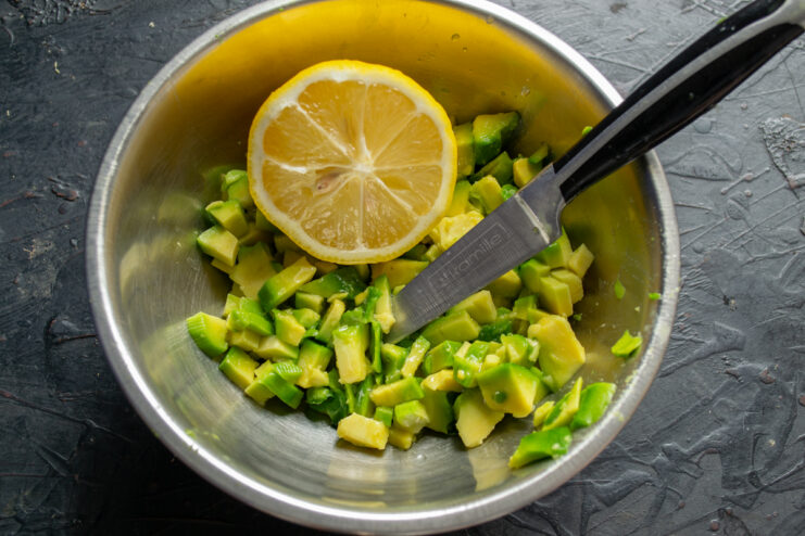 Dressing The Avocado Filling Diced avocado in a bowl drizzled with lemon juice and extra virgin olive oil