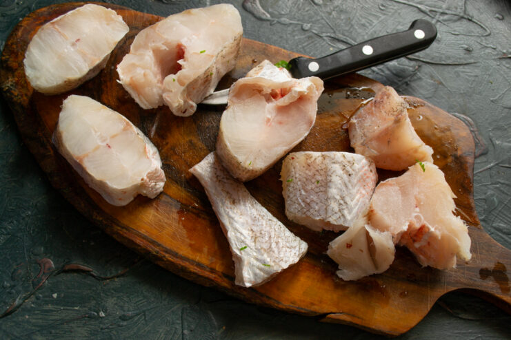 Preparing the fish Sliced fresh white fish fillets on a wooden cutting board