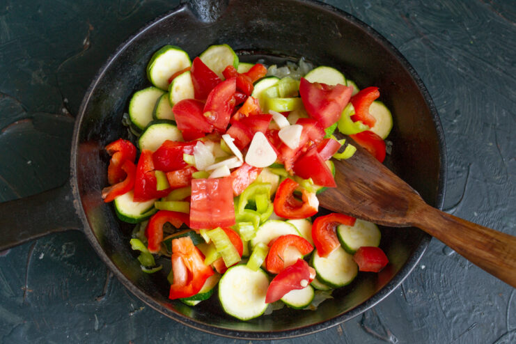 Adding the Tomatoes Diced ripe red tomatoes cooking with the vegetable mixture in a pan