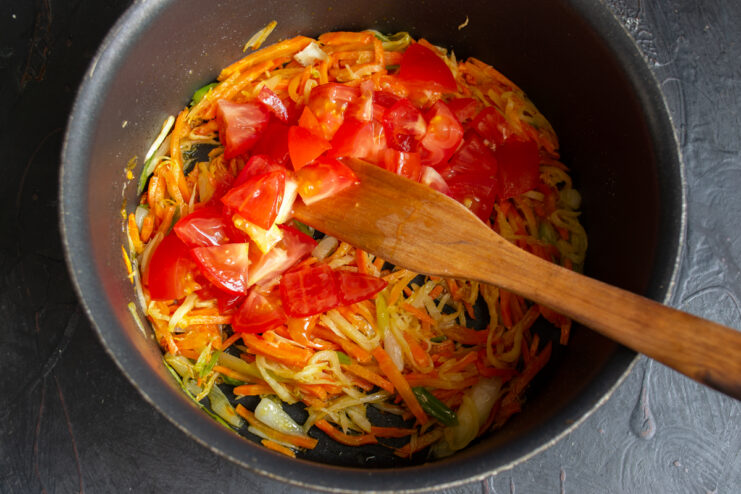 Adding Tomatoes To The Base Diced fresh tomatoes added to the sautéed vegetables in the pot.