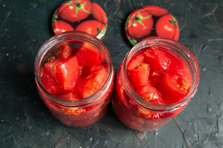 Packing tomato slices into the jars Glass canning jars tightly packed with chopped fresh tomatoes