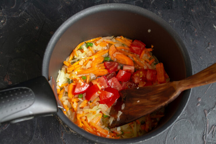 Adding tomatoes Diced tomatoes added to the vegetable mixture in the pot.