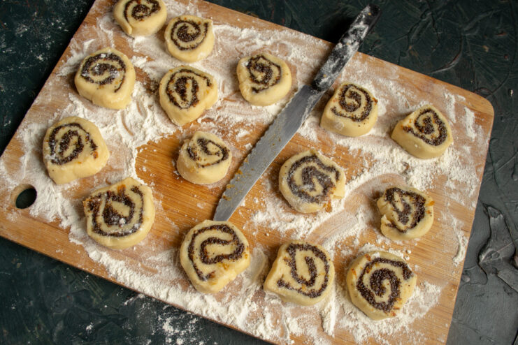 Slicing the Cookies Sliced raw poppy seed cookie rounds placed on a cutting board