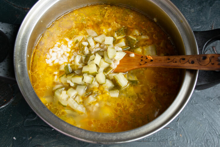 Adding fermented sour pickles Adding diced fermented sour pickles into the pot of soup