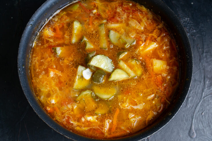 Adding Fermented Pickles Sliced fermented pickles in a pot of simmering rassolnik.