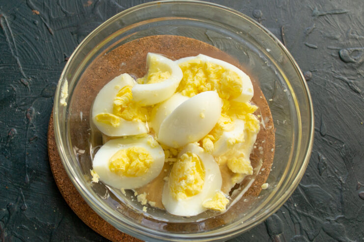 Adding eggs to the dressing Chopped boiled eggs added to the bowl with dressing ingredients