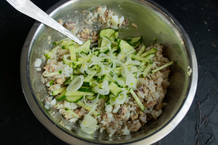 Adding blanched onions Sliced white onion added to a mixing bowl with salad ingredients