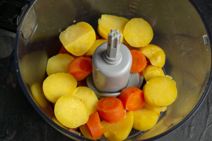 Processing The Vegetables Chopped potatoes and carrots placed in a food processor bowl