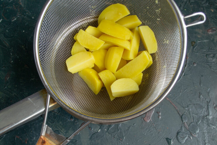 Draining parboiled potatoes Potato wedges resting in a metal sieve