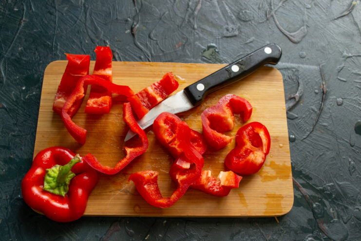 Adding Bell Pepper Chopped chunks of sweet red bell pepper scattered on a wooden board.