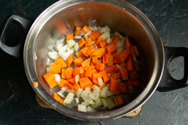 Chopped onions and carrots placed in a cooking pot for the soup base