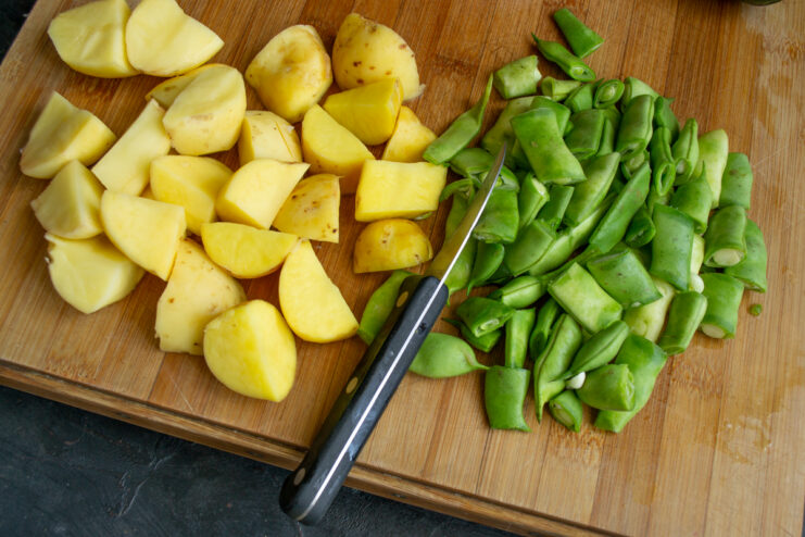 Chopped new potatoes and green beans on a wooden cutting board