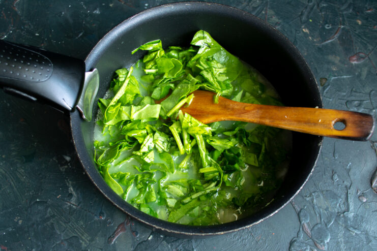 Adding fresh spinach to the boiling soup base