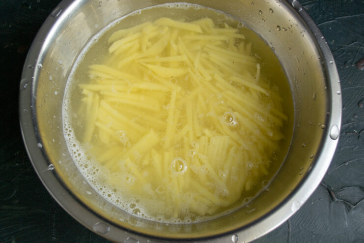 Rinsing the shoestring potatoes Shoestring potatoes in a bowl of cold water