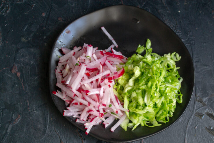 Julienned radishes arranged next to the cabbage