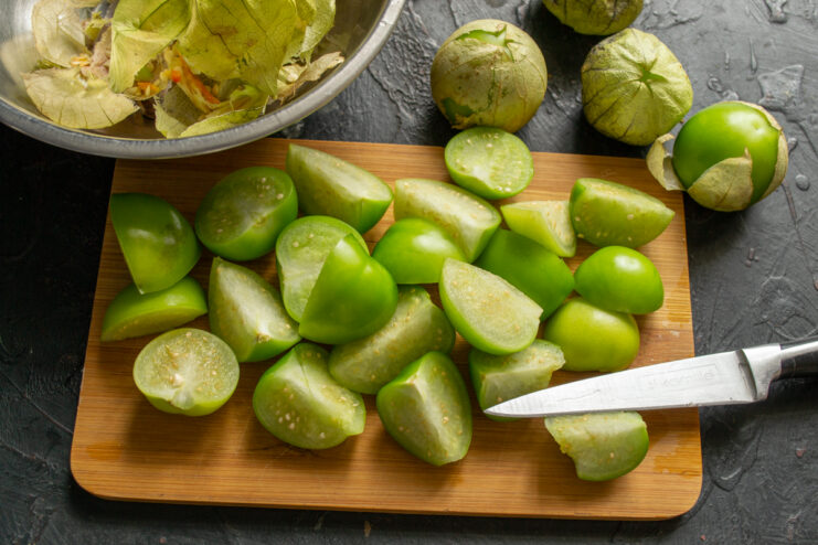 Prepping the physalis Sliced green vegetable physalis resting on a wooden cutting board