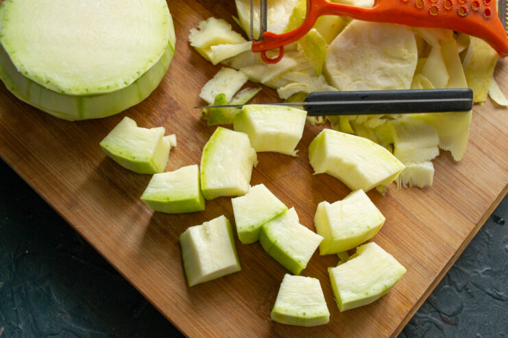 Prepping the zucchini Dicing peeled zucchini into cubes on a wooden cutting board