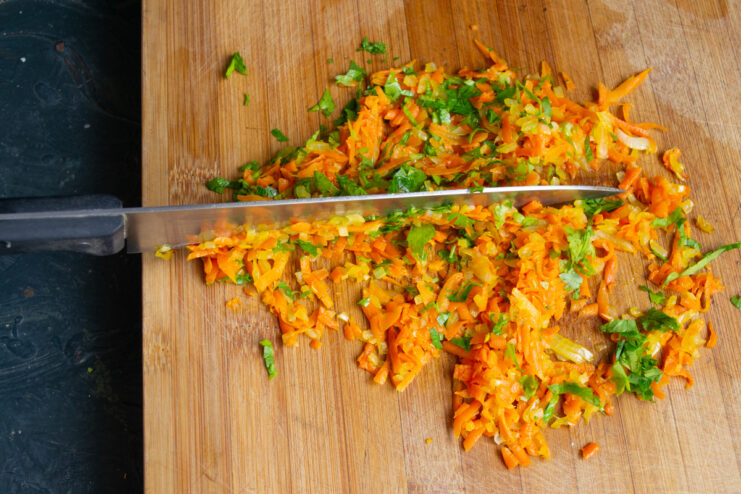 Chopping sautéed vegetables and fresh parsley on a board