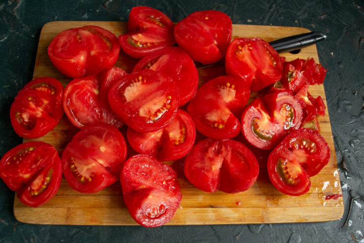 Slicing peeled tomatoes into bite-sized pieces Slicing peeled red tomatoes into quarters and removing the cores