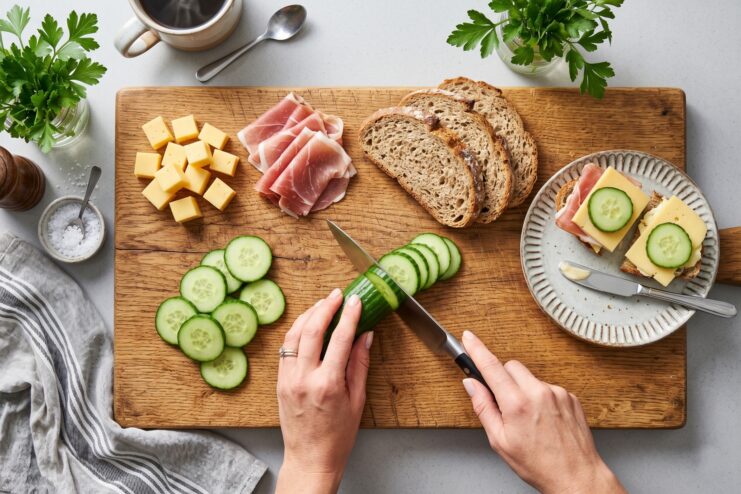 Slicing fresh green cucumbers with a medium-sized utility knife