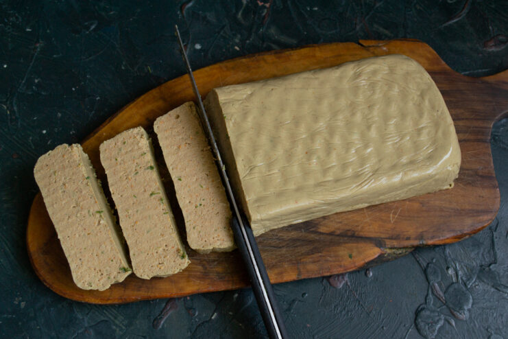 Slicing the finished dish Slicing a block of firm chicken liver pâté into thick, smooth portions.